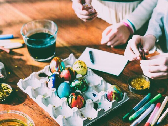 Kinder färben und bemalen Eier.